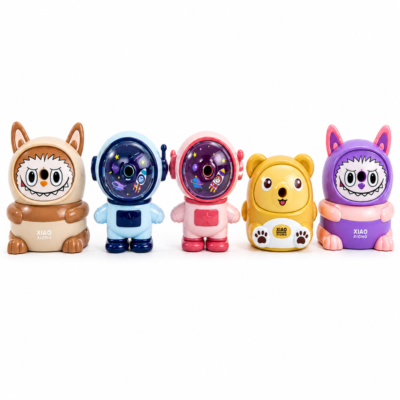 A set of five cute cartoon pencil and crayon sharpeners including a brown monster, a blue astronaut, a pink astronaut, a yellow bear, and a purple monster.